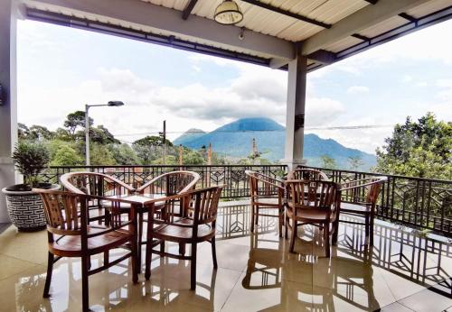 a table and chairs on a balcony with a view of mountains at Avila Ketapan Rame Hotel in Trawas