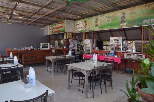 une salle à manger avec des tables et des chaises dans un restaurant dans l'établissement โคบาล ห้องพักรายวัน, à Chom Thong