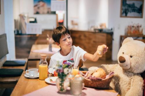 a young boy sitting at a table with a teddy bear at Hotel Andres in Bamberg
