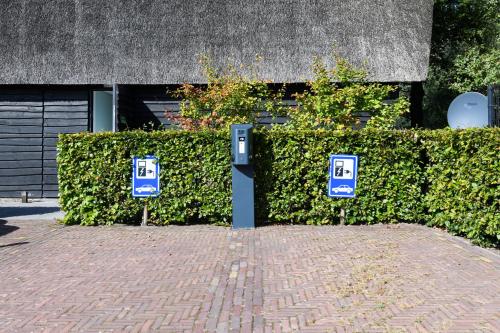a hedge with two parking meters in front of a building at Hotel De Roode Schuur in Nijkerk