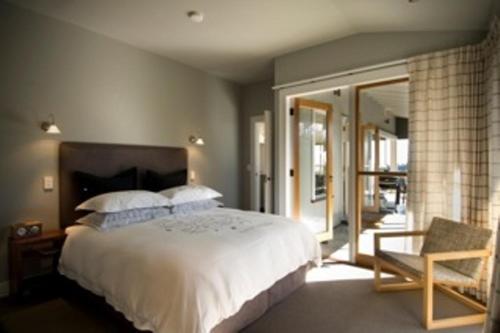 a bedroom with a large white bed and a chair at Millar Road in Hastings