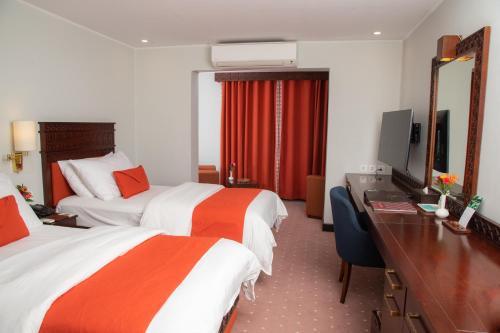 a hotel room with two beds and a desk at Gilgit Serena Hotel in Gilgit