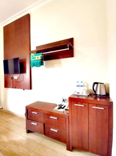 a kitchen with a wooden cabinet and a mirror at Avila Ketapan Rame Hotel in Trawas