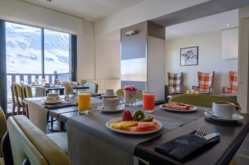 a dining room with two tables with fruit on plates at Hotel Caribou in Pas de la Casa