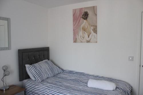 a bedroom with a bed and a painting on the wall at Exquisite and Modern 2 bed Maisonette in Harmondsworth
