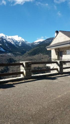 a wooden fence in front of a house with mountains at Δωμάτια με θέα in Méga Khoríon