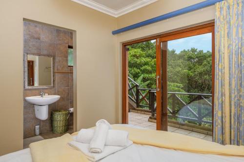 uma casa de banho com uma cama, um chuveiro e uma janela. em San Lameer Villa 11703 - 5 Bedroom Luxury - 10 pax - San Lameer Rental Agency em Southbroom