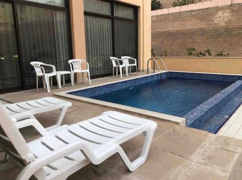 a swimming pool with white chairs and a whitevisorvisor at 3 Bed rooms Villa at Mina Alfajer Resort Dibba - Al-Fujairah in Rūl Ḑadnā