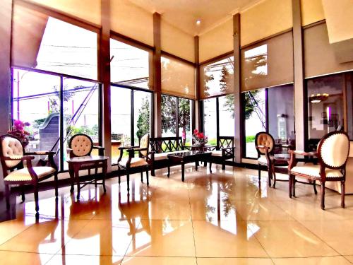 a lobby with chairs and tables and large windows at Avila Ketapan Rame Hotel in Trawas