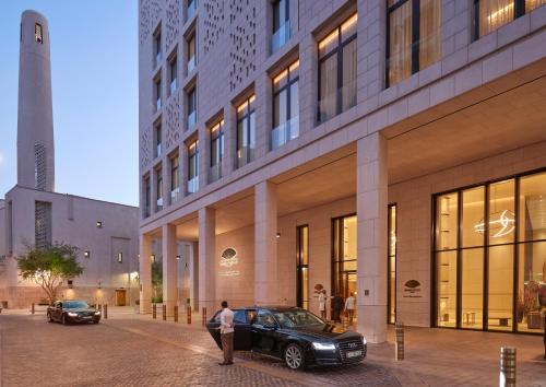 a man standing next to a car in front of a building at Mandarin Oriental, Doha in Doha