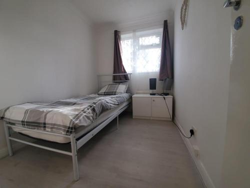 Habitación pequeña con cama y ventana en 2 Bedroom Flat near Heathrow airport en Yiewsley