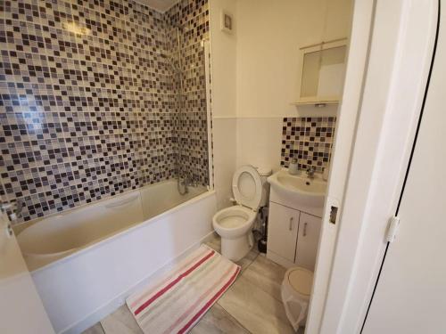 La salle de bains est pourvue d'une baignoire, de toilettes et d'un lavabo. dans l'établissement 2 Bedroom Flat near Heathrow airport, à Yiewsley