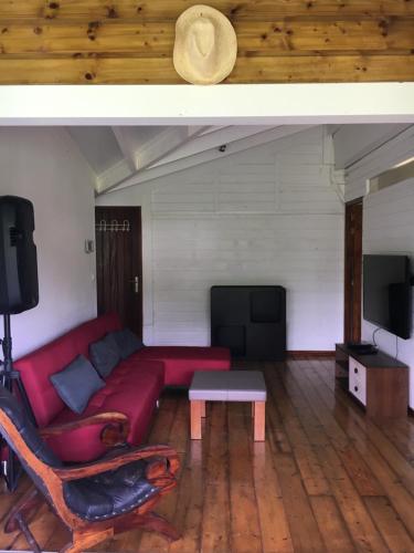 salon z czerwoną kanapą i telewizorem z płaskim ekranem w obiekcie LOFT ET VERDURE w mieście Fort-de-France