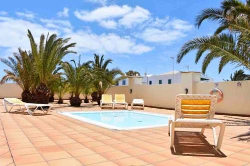 a patio with a pool and chairs and palm trees at Riviera Park 7A - Air con- Wi-Fi- UK channels- 5 minutes walking from the sea in Tías