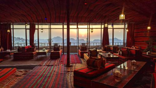 Habitación grande con sofás, mesas y ventanas. en Rocky Mountain Hotel, en Wadi Musa