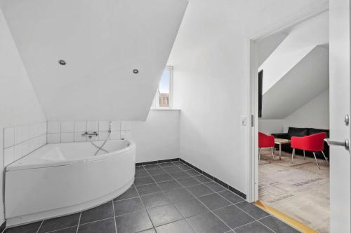 a white bathroom with a tub and red chairs at Best Western ToRVEhallerne in Vejle