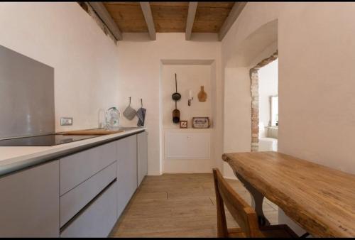 Corte del Cedro في بروفاغليو دلسيو: مطبخ بدولاب بيضاء وطاولة خشبية