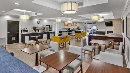 a restaurant with tables and chairs and a kitchen at Comfort Suites Salisbury I-85 in Salisbury
