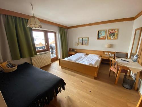 a bedroom with a bed and a table and a window at Stammhaus im Hotel Alpine Palace in Saalbach Hinterglemm