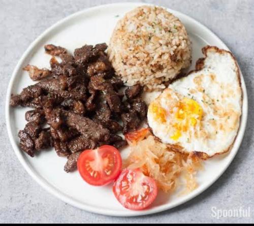 a plate of breakfast food with eggs meat and tomatoes at La Casa Blanca Binoclutan in Botolan
