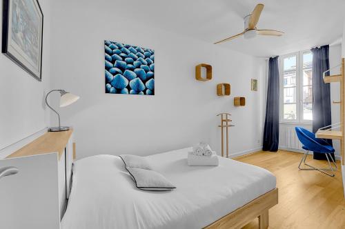 um quarto com uma cama branca e uma cadeira azul em L'île aux Tounis - T3 Moderne centre de Toulouse em Toulouse