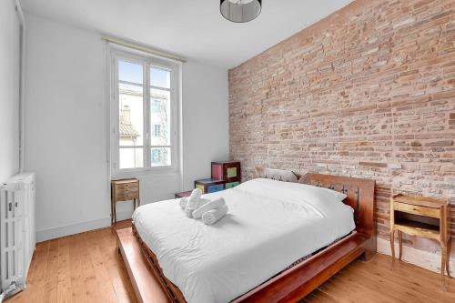 um quarto com uma parede de tijolos e uma cama em Rare pearl very quiet and bright in Toulouse em Toulouse