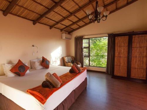 um quarto com uma cama grande e uma janela grande em Nghunghwa Lodge em Vila Praia do Bilene