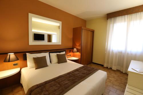 a hotel room with a bed and a mirror at RHI Porta Bologna in Pieve di Cento