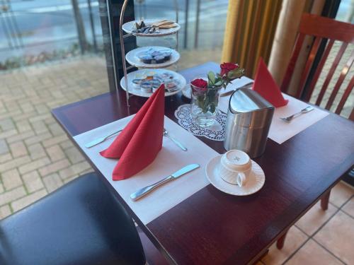 Hotel Villa Sophia في فارندورف: طاولة خشبية عليها مناديل حمراء وصحون