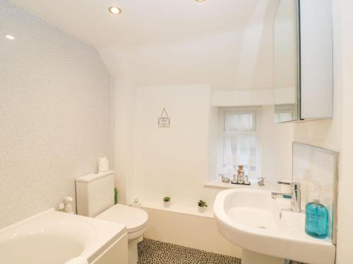 a white bathroom with a toilet and a sink at Barton Cottage in Cheltenham