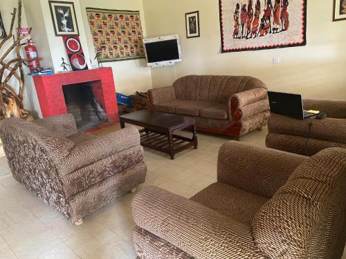 a living room with couches chairs and a fireplace at Ranges View Lodge Staycation in Kiamuturi