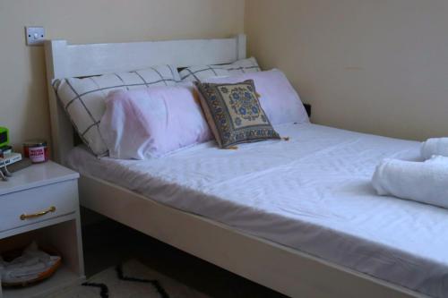 ein Bett mit weißer Bettwäsche und einem Kissen darauf in der Unterkunft Lux Suites Mtwapa Studio Apartment-2 in Mtwapa
