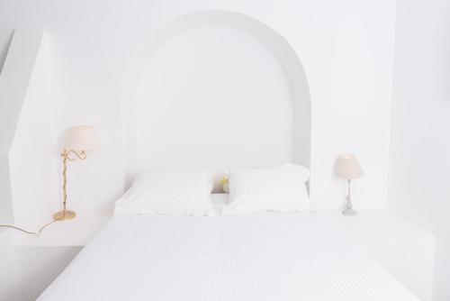 a white bedroom with white bedding and two lamps at Kontseta in Mérikhas