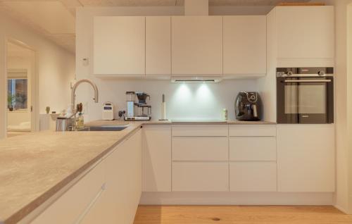 a white kitchen with white cabinets and appliances at Bright 2BR apartment, great view in Tórshavn