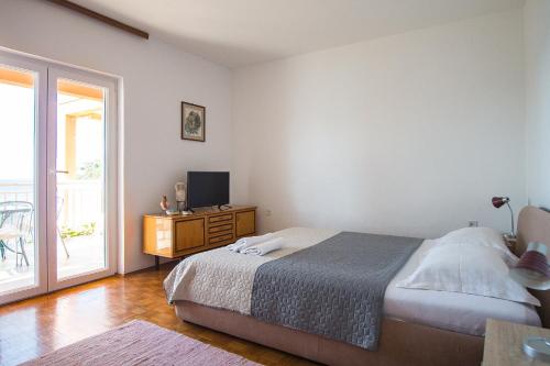 a bedroom with a bed and a television and a balcony at Lemon tree in Podaca