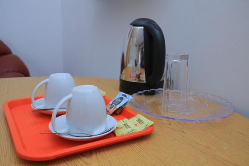 a red tray with cups and a coffee maker on a table at Frontiers Hotel & Conference Entebbe in Entebbe