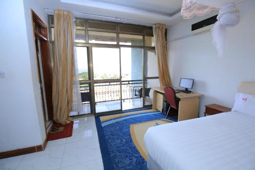 Cette chambre comprend un lit, un bureau et une fenêtre. dans l'établissement Frontiers Hotel & Conference Entebbe, à Entebbe