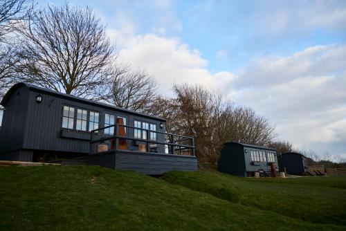 a house on top of a grassy hill at Hog Deer Creek - At Port Lympne Reserve in Hythe