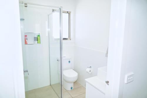 a bathroom with a toilet and a glass shower at Modern style unit 2 Deer Park in Deer Park