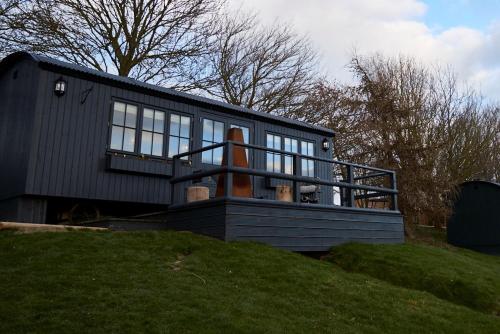 a black tiny house sitting on top of a hill at Hog Deer Creek - At Port Lympne Reserve in Hythe