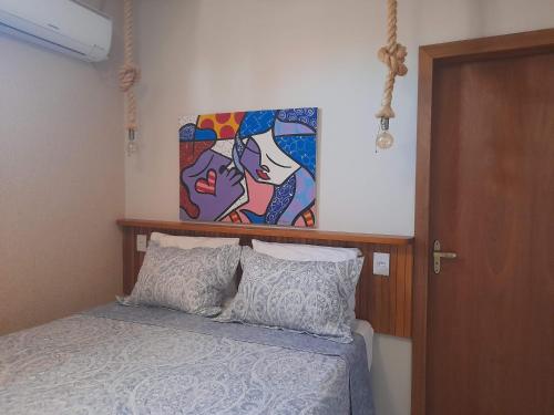 a bedroom with a bed with a painting on the wall at Suítes Pirenópolis Piri in Pirenópolis