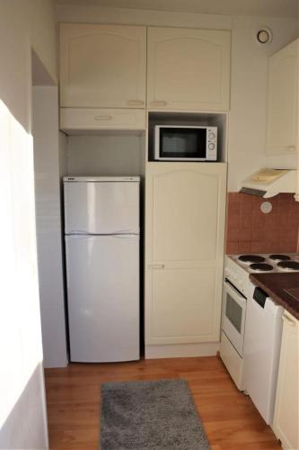 a kitchen with a white refrigerator and a microwave at Studio middle of town centre. in Tornio