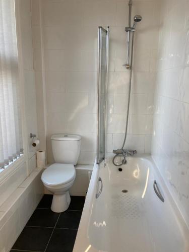 a white bathroom with a toilet and a tub at Coniston Guest House in Sheffield