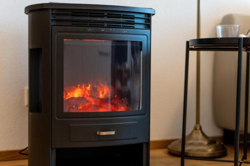 a black stove with a fire in a room at Faschina Apartment - Top 1 in Fontanella