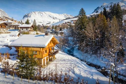 a log cabin in the snow with mountains in the background at Lodge le Chevreuil - OVO Network in Le Grand-Bornand