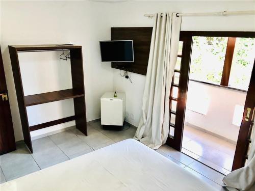 a room with a bed and a tv and a window at Princesinha do Sul in Ilhéus