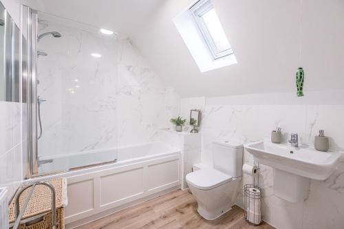 a white bathroom with a tub and a toilet and a sink at 10 Acorn Close Aldringham in Leiston