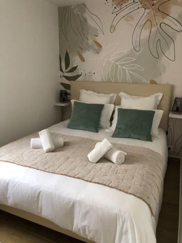 - un grand lit blanc avec des oreillers verts et blancs dans l'établissement Le Bigorn'O : T2 situé à 50 m de la plage, à Concarneau