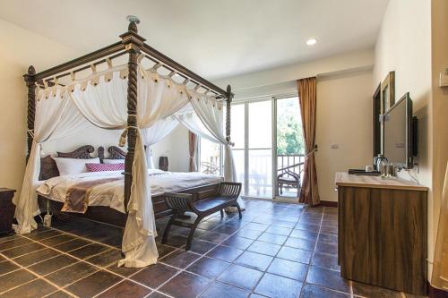 南庄的住宿－幸福綠光峇里島渡假會館，一间卧室设有一张天蓬床和一个阳台