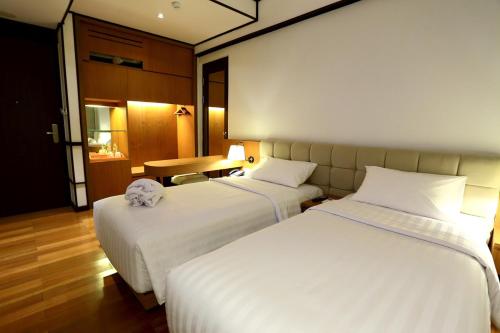 a hotel room with two beds and a table at Namin Dago Hotel in Bandung